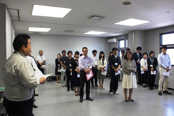 男性職員が代表で話をして、それを他の職員は並んで話を聞いている写真