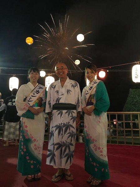 着物姿のデカンショ観光大使2名にはさまれた市長の後ろに花火が綺麗な写真