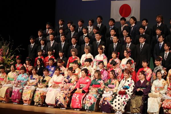 振袖を着た女性が前に座り、その後ろにスーツを着た男性が並んで立っている新成人の集合写真