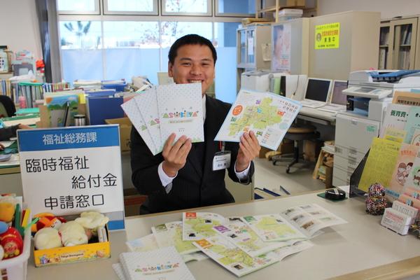 福祉総務課の男性が両手にガイドブックを持っている写真