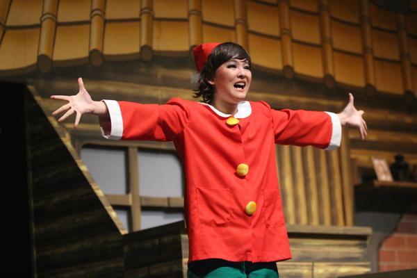 真っ赤な衣装を着た女性が両手を広げ歌っている写真