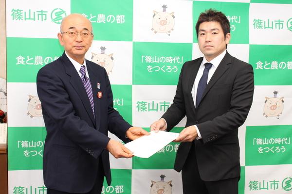 市長と、菟原 元彦委員長が一緒に書類を持っている写真