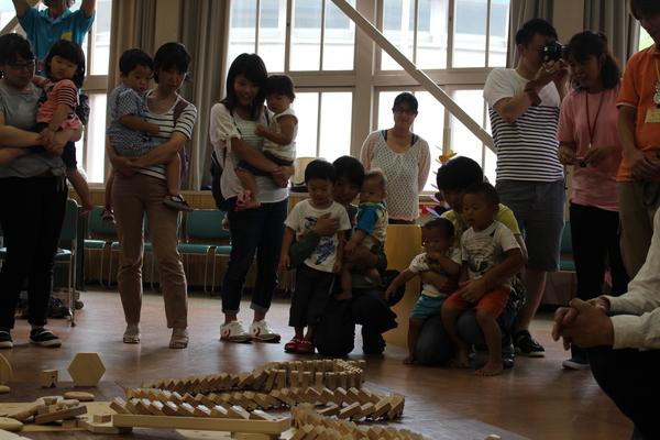 木育キャラバンで六角形の木材で作られたドミノが倒れている様子を親子が見ている写真