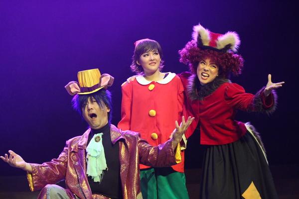 左に両手を広げ、右に左手を広げ右手はピノキオに肩を組んだ壊そうな2人の間に悲しそうなピノキオの写真