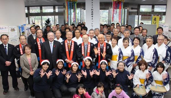 市長の周りに、サンタの赤い帽子を被った女性やデカンショ踊りの着物を着た人、関係者、祝賀セレモニーに集まった市民の皆さんが集まって写っている集合写真