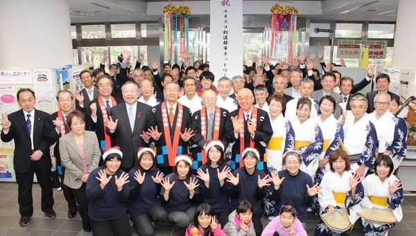 法被姿の市長や、サンタの帽子を被った女性達、着物姿の女性達などが並んでいる集合写真