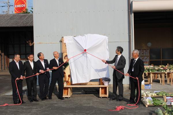 中央に白い幕がかけられ、中の物が見えないようになっており、白い幕を6名の男性が紐で引っ張っている写真