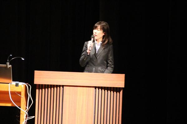 壇上の上で女性職員がお話している写真