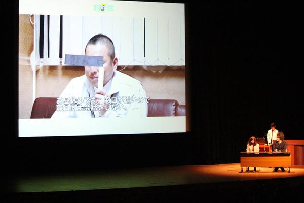スクリーンに男性がモザイクを手作りで作って会社の悩みを話している写真