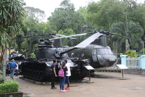 展示されているヘリコプターと戦車の前にいる男女の写真