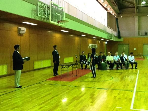 体育館に座っている来賓者の前で女子学生が選手宣誓をしている写真