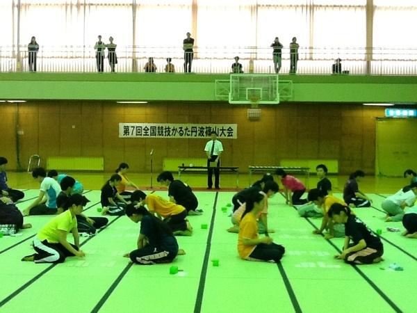 審判が立ち体育館に敷かれている畳の上でかるた大会が行われている様子を2階の通路から見ている観客まで写した写真