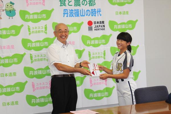 市長から、笑顔で奨励金を受け取っているユニフォーム姿の女の子の写真