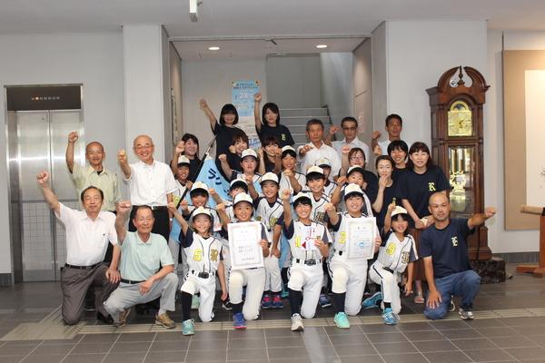 市長、関係者とラクーンズ・ジュニアのメンバーが、右手を上にあげるポーズをとる集合写真