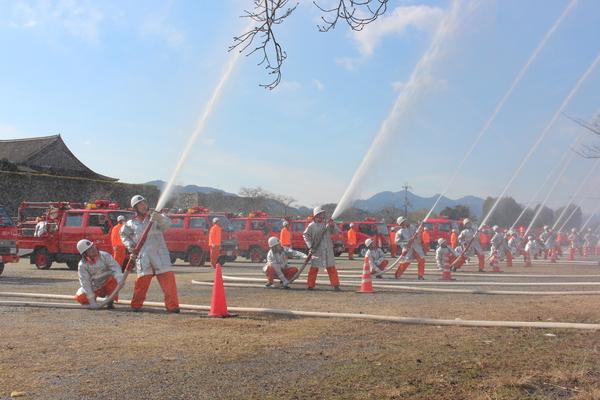 消防団員が空に向かって放水演習をしている写真