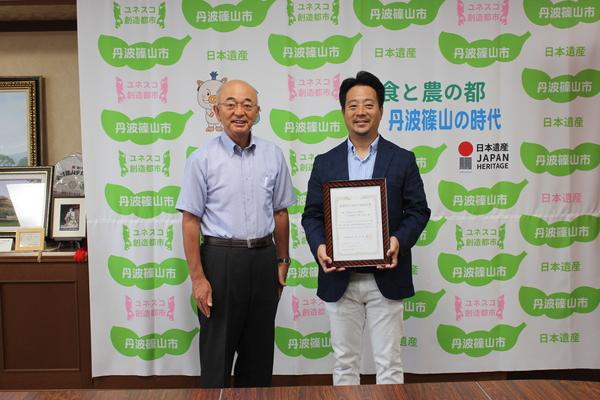 丹波篠山たけし農産の中島さんが額を持って市長と記念撮影している写真