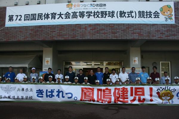 横断幕を持ち、球場の前に並ぶ選手と関係者の集合写真