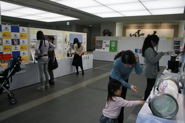 沢山のお客さんが展示品を見ており、親子連れの小さい女の子が興味を持って指さしして見ていたり、パンフレットに目を通している女性が写っている写真
