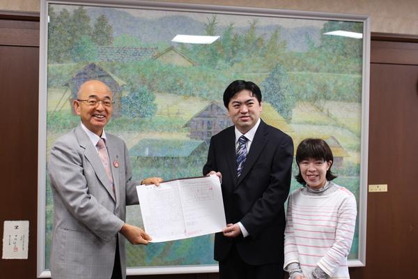 篠山市結婚相談室で22組目となるお二人、牛窪 俊人さんと澤田 淳美さんが市長と一緒に婚姻届を持っている写真
