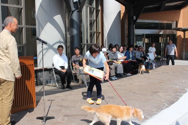右手に賞状を持ち、左手には長寿犬のリードを持っている飼い主さんとその様子をみている他の表彰者の写真