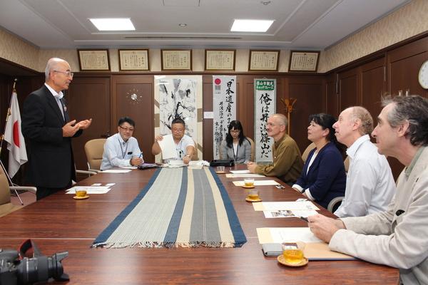 応接室にて、外国人と関係者を前に、立って話をしている市長の写真