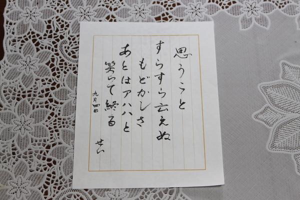 ご高齢の女性が紙に書かれたものがテーブルに置かれている写真