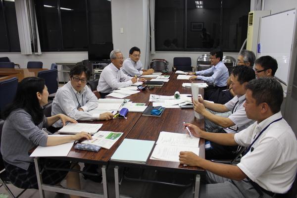 市名検討を調査する職員9名が机に資料を広げ、活発に意見交換をしている様子の写真