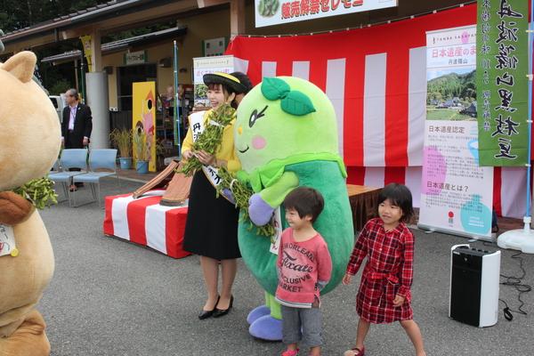 大使の女性とまめりんの着ぐるみと小さい男の子と女の子が立っている写真