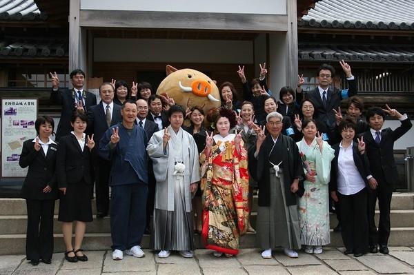 篠山城跡で、新郎新婦とまるいの、関係者がピースサインをしている集合写真