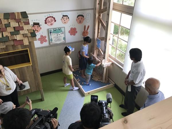 木で作られた縦長の遊具で子供3人が遊んでいて、それをテレビカメラが撮影している写真