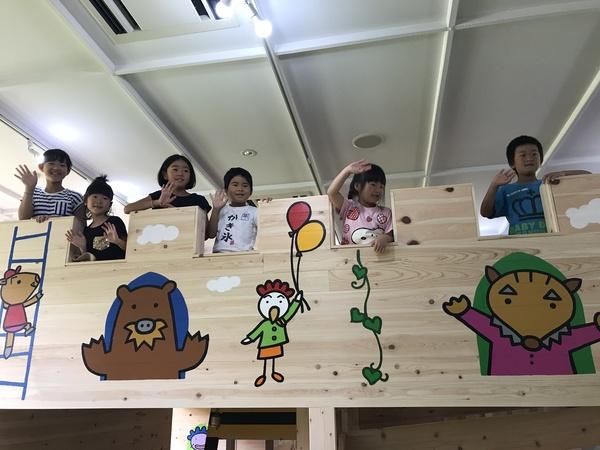 木で出来ていて、イノシシやにわとりの絵が書かれたロフトから子供たちが顔を出して手を振っている写真