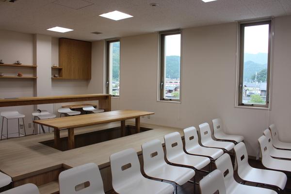 手前には15脚ほどの椅子が置いてあり、奥には掘りごたつ式の木のテーブルが置かれてある写真