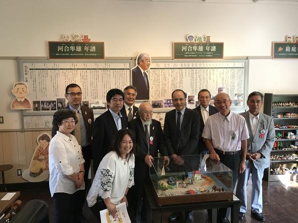 ジオラマを囲んで9名の男女と市長が並んでいる集合写真