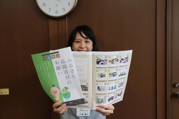 ふるさと納税制度のチラシを持って笑顔で写っている女性の写真