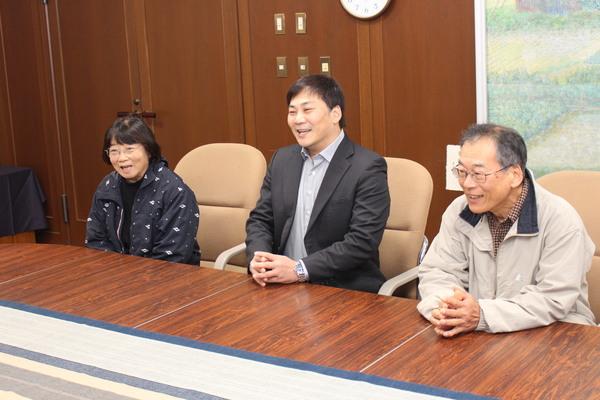 田中 美央さんと両親が机に並んで座って談笑している写真