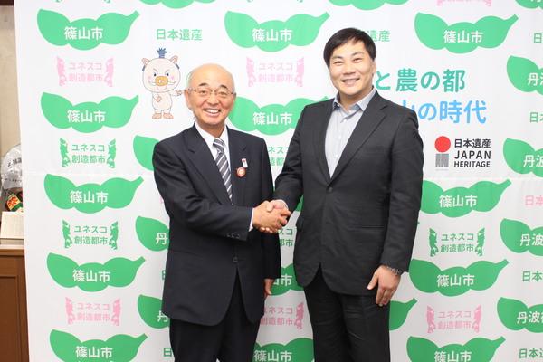 田中 美央さんと市長が握手をして記念撮影している写真