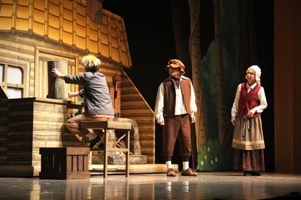 左に椅子に座り木を触っていて、それを見ている男性と女性の写真