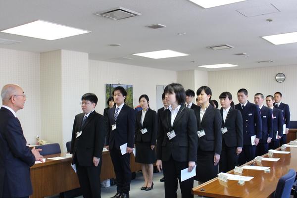 15名の新規職員が2列に並び前にいる市長の話しを聞いている様子の写真