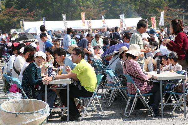 飲食コーナーでたくさんの人達が椅子に座り食事をして満席で賑わっている写真