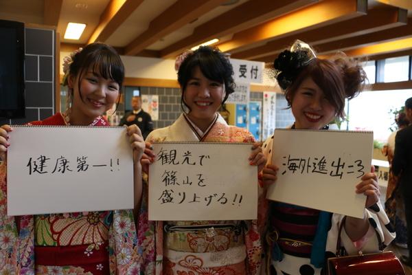 「健康第一!!」、「観光で篠山を盛り上げる!!」「海外進出」と書いた画用紙を手に持って胸の前に持って写っている、振袖を着た新成人3名の写真