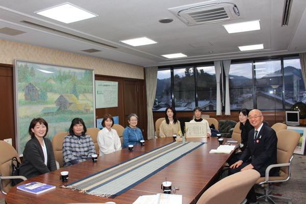 賞状の入った額を持った中野母親クラブの方と市長らがテーブルに座って一緒に記念撮影している写真