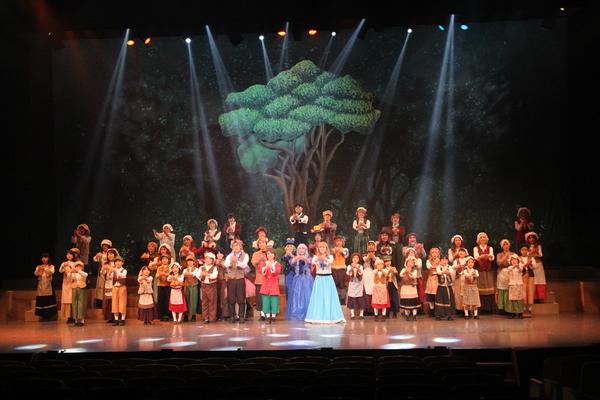 両手を胸元で組み、出演者の集合写真