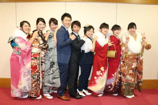 中央にスーツを男性2名とスーツを着た女性1名がおり、両脇に振袖を着た女性が肩に手を置いて連なって写っている写真