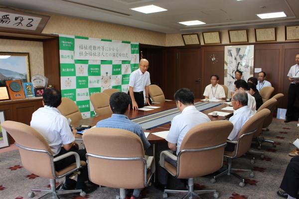 応接室で、座って市長の話を聞く男女の写真