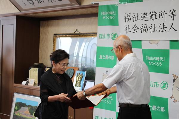 市長から、調印書を受けとる女性の写真