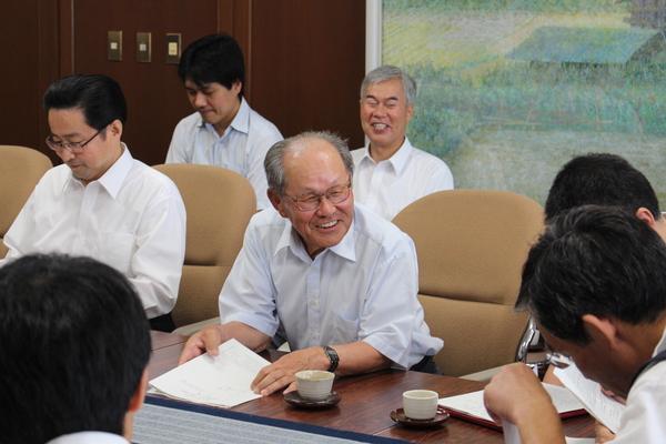 資料を見ている男性に向かって、笑顔で話をしているご年配の男性の写真