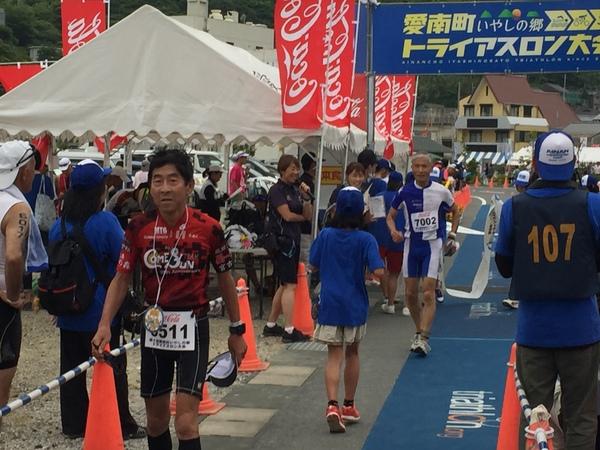 赤いランニングウェアを着た男性とその後ろを青と白の縞々のウェアを着た男性が歩いている写真