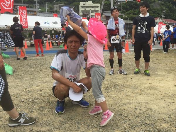 安福 直剛さんがしゃがんで、ピンクの帽子を被った女の子が頭にタオルをかぶせようとしている写真