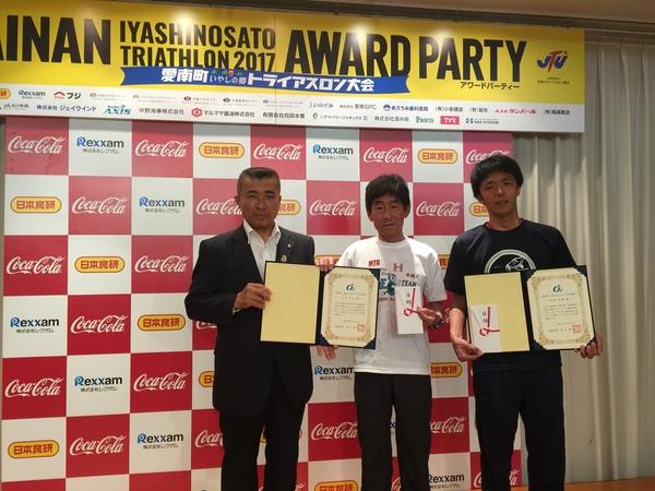 愛南町のトライアスロン大会の表彰で篠山市民の山田幸広さん、安福直剛さんが賞状と祝い袋を手に持ち記念写真