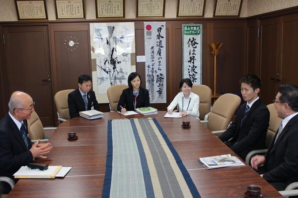 会議テーブルに座る、市長とスーツを着た男女の写真